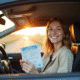 Jeune adulte souriant avec permis de conduire dans une voiture moderne